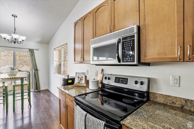 kitchen featuring dark wood-type flooring, brown cabinetry, lofted ceiling, stainless steel appliances, and a notable chandelier