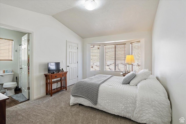 bedroom with ensuite bathroom, carpet floors, baseboards, and lofted ceiling