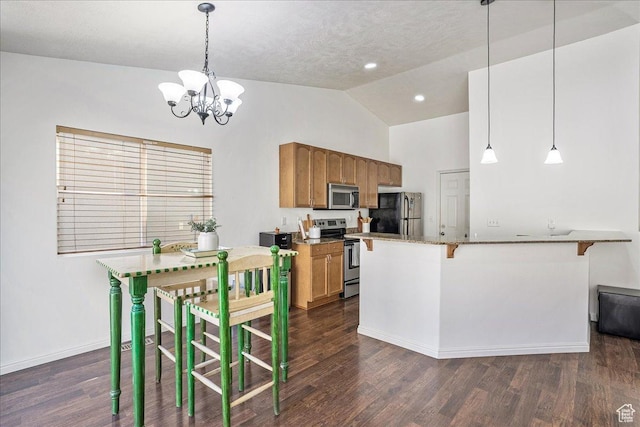 kitchen featuring brown cabinetry, dark wood-type flooring, vaulted ceiling, stainless steel appliances, and a notable chandelier