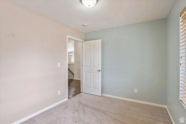unfurnished bedroom with a textured ceiling, baseboards, and carpet floors