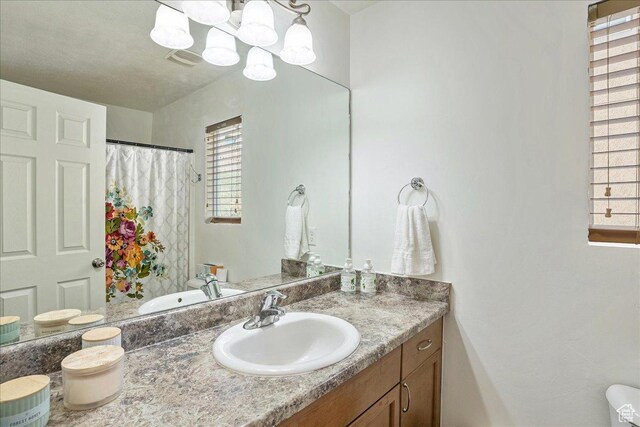 full bath with a shower with shower curtain, vanity, and an inviting chandelier