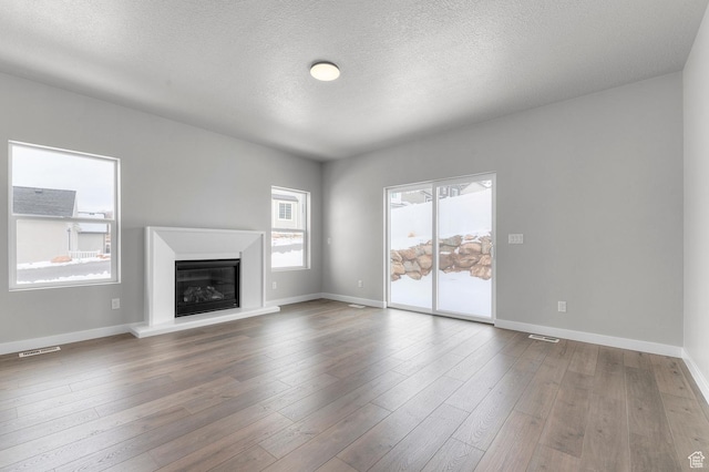 unfurnished living room with a textured ceiling and hardwood / wood-style floors