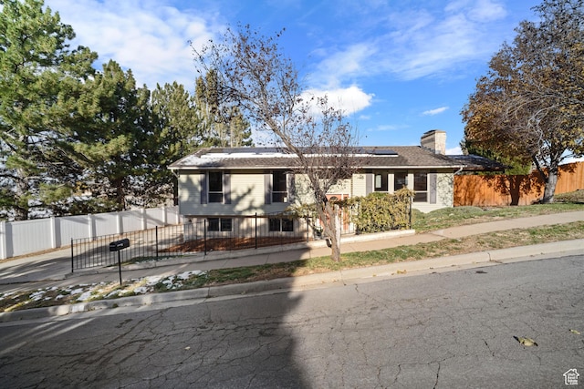 151 S Bernice Way N, Salt Lake, UT 84054 - view of front of home featuring solar panels, driveway, a chimney, and a fenced front yard