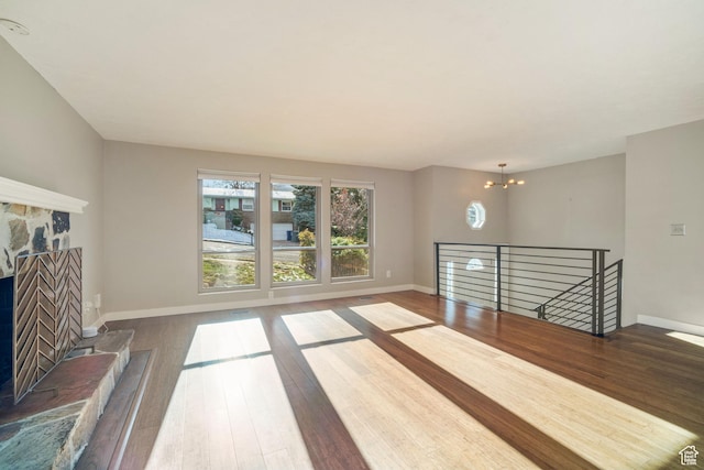 151 S Bernice Way N, Salt Lake, UT 84054 - unfurnished living room featuring a stone fireplace, wood finished floors, a chandelier, and baseboards