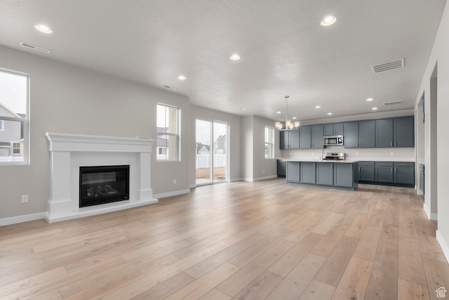 1849 S 2475 W, West Haven, UT 84401 - unfurnished living room with an inviting chandelier and light hardwood / wood-style flooring