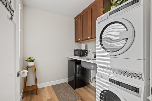 6443 W Early Bird Dr, South Jordan, UT 84009 - laundry area with stacked washer and clothes dryer, cabinet space, light wood-style floors, and baseboards