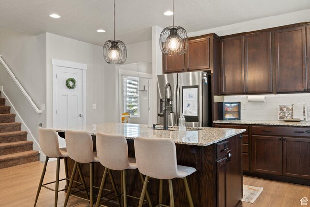 6443 W Early Bird Dr, South Jordan, UT 84009 - kitchen with stainless steel refrigerator with ice dispenser, light wood-style floors, a kitchen bar, a center island with sink, and tasteful backsplash