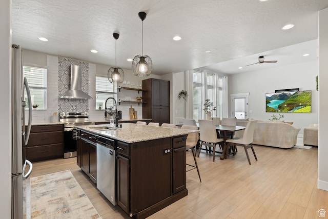 6443 W Early Bird Dr, South Jordan, UT 84009 - kitchen with wall chimney exhaust hood, appliances with stainless steel finishes, a sink, a kitchen breakfast bar, and dark brown cabinets