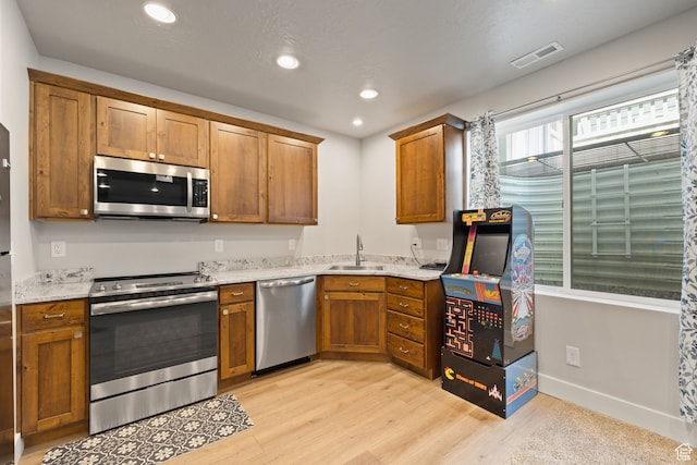 6443 W Early Bird Dr, South Jordan, UT 84009 - kitchen featuring stainless steel appliances, a sink, light wood finished floors, brown cabinetry, and recessed lighting