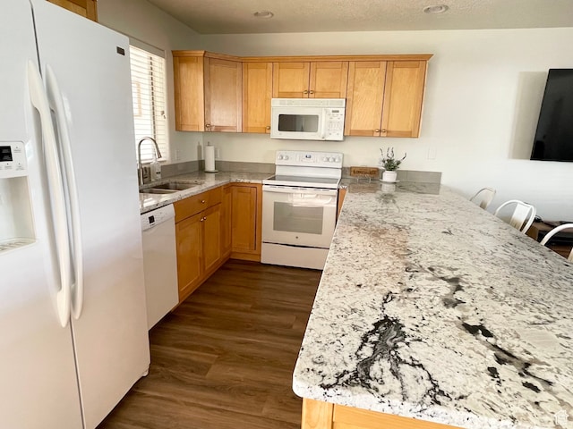 kitchen with kitchen peninsula, light stone countertops, white appliances, dark wood-type flooring, and sink