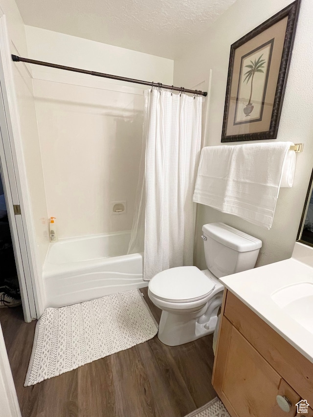 full bathroom with hardwood / wood-style floors, vanity, toilet, a textured ceiling, and shower / tub combo with curtain