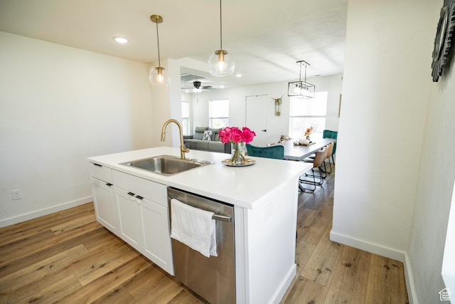 kitchen with stainless steel dishwasher, light hardwood / wood-style floors, sink, and a kitchen island with sink
