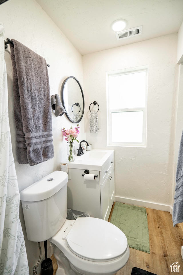 bathroom with toilet, vanity, and hardwood / wood-style flooring