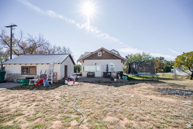 back of house with a yard and a trampoline