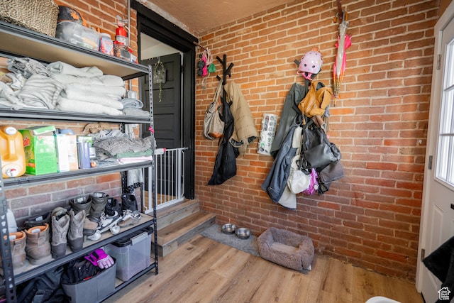 mudroom with wood-type flooring and brick wall