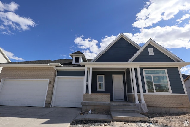 view of front facade featuring covered porch, brick siding, driveway, and an attached garage