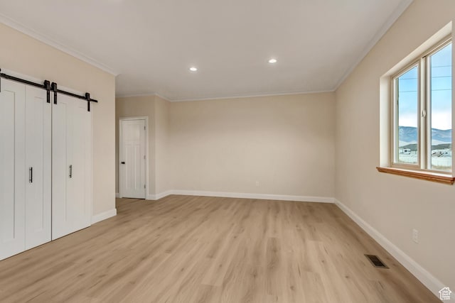 408 Rigdon St, Grantsville, UT 84029 - unfurnished bedroom featuring a barn door, light wood-style flooring, ornamental molding, recessed lighting, and baseboards