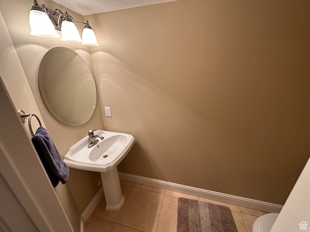 bathroom with tile patterned flooring, baseboards, and a textured ceiling