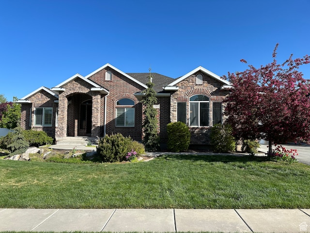 view of front of home with stone siding, brick siding, and a front lawn