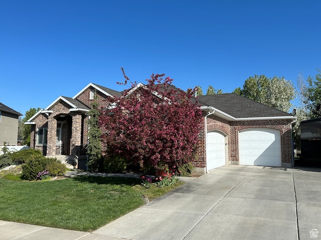 view of front of house with driveway, a front yard, brick siding, a garage, and a shingled roof