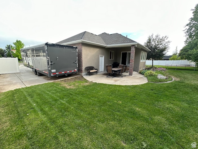 rear view of property with fence, a patio, a trampoline, brick siding, and a lawn