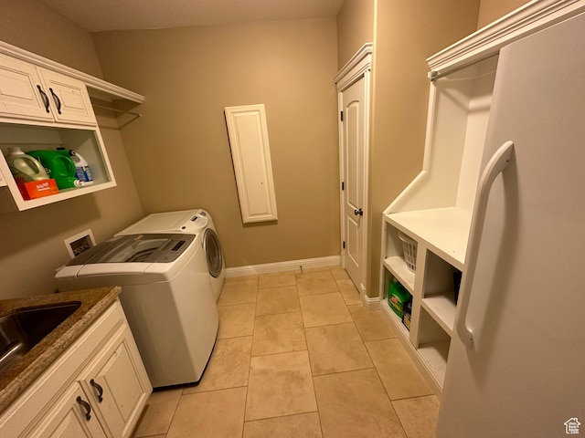 laundry area featuring light tile patterned floors, baseboards, washing machine and clothes dryer, a sink, and cabinet space