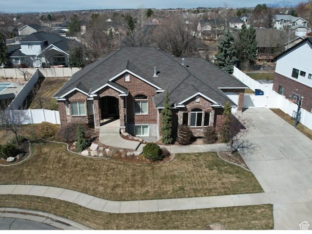 view of front of property with brick siding, a front yard, driveway, and fence