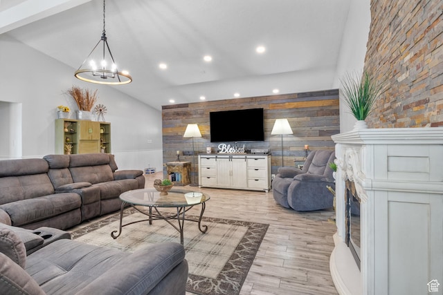 living area featuring an accent wall, recessed lighting, an inviting chandelier, light wood-style floors, and high vaulted ceiling