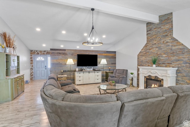 living area with recessed lighting, a warm lit fireplace, an accent wall, beamed ceiling, and light wood-type flooring