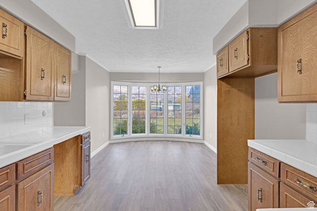4866 Adams Ave, South Ogden, UT 84403 - kitchen with crown molding, light wood-type flooring, a textured ceiling, decorative light fixtures, and a chandelier