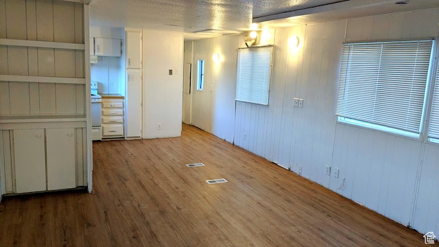 spare room with wood walls, light hardwood / wood-style floors, and a textured ceiling