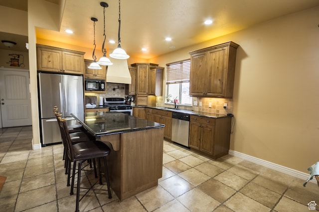 kitchen featuring appliances with stainless steel finishes, a center island, pendant lighting, and backsplash