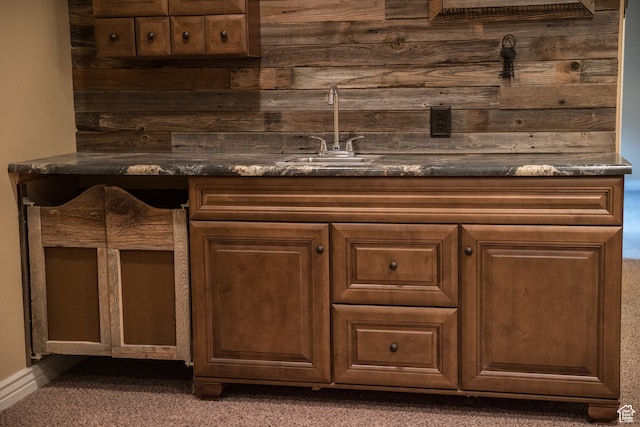 bar featuring dark colored carpet, sink, and wooden walls