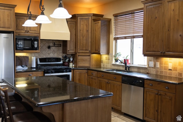 kitchen with pendant lighting, premium range hood, sink, decorative backsplash, and stainless steel appliances