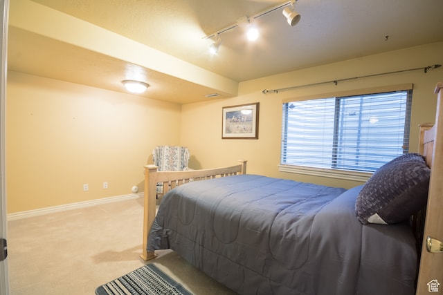 bedroom with light colored carpet and rail lighting
