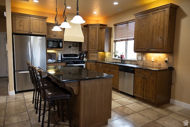 kitchen featuring sink, stainless steel appliances, tasteful backsplash, decorative light fixtures, and a kitchen island