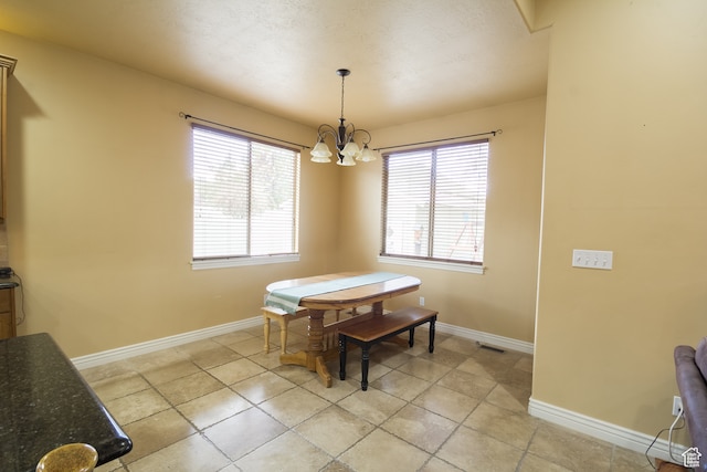 tiled dining area featuring plenty of natural light and a chandelier