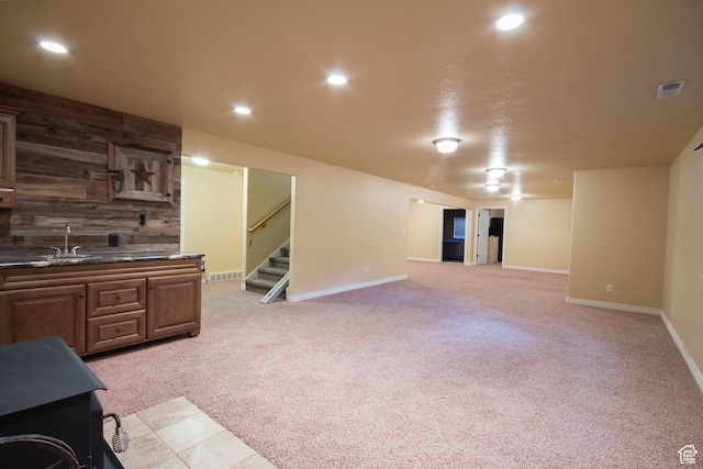 living room featuring light carpet, wet bar, and wooden walls