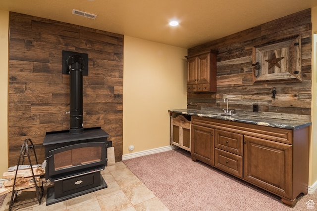 kitchen featuring dark stone countertops, wood walls, sink, and light carpet