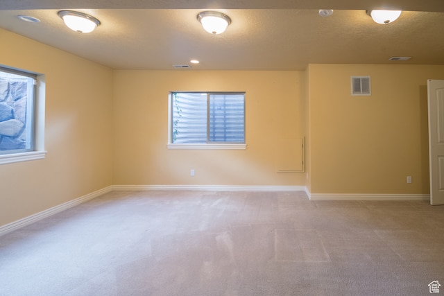 unfurnished room featuring light colored carpet and a textured ceiling