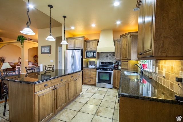 kitchen featuring a kitchen bar, appliances with stainless steel finishes, a center island, and custom range hood
