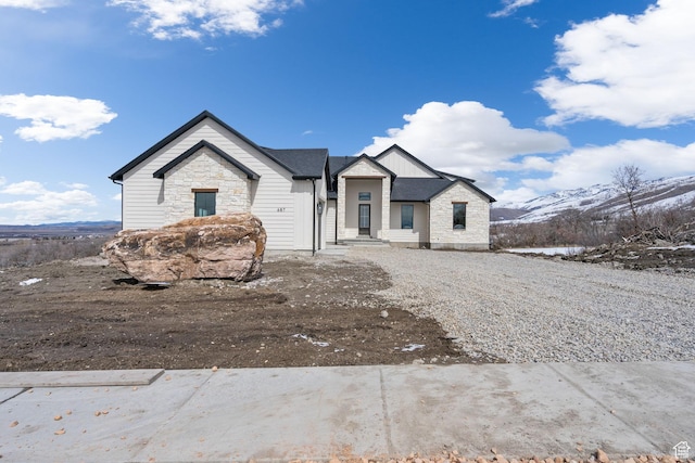 view of front of house with gravel driveway, a mountain view, and stone siding