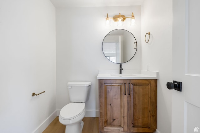 bathroom featuring toilet, vanity, baseboards, and wood finished floors