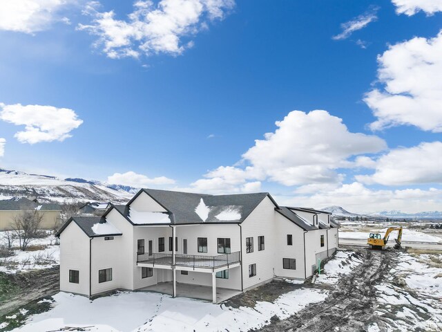 snow covered back of property featuring a mountain view