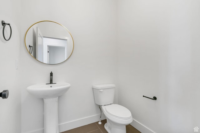 bathroom featuring tile patterned floors, toilet, baseboards, and a sink