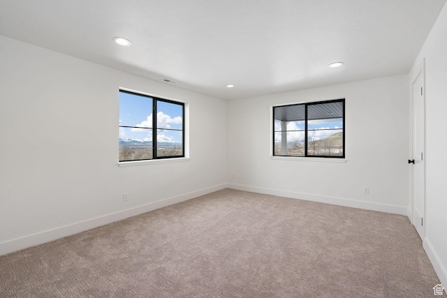 empty room featuring recessed lighting, baseboards, and light carpet