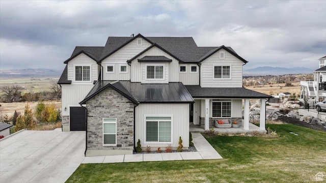 615 N 750 E, Hyde Park, UT 84318 - view of front of property featuring a standing seam roof, stone siding, a front lawn, concrete driveway, and an attached garage