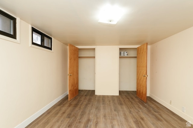 unfurnished bedroom with hardwood / wood-style floors and multiple closets