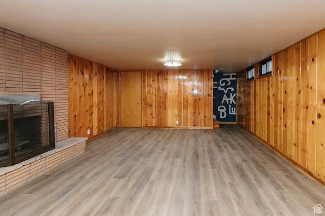 basement featuring hardwood / wood-style flooring, a brick fireplace, and wooden walls