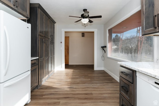 kitchen with white appliances, light stone counters, dark brown cabinetry, and dark wood-type flooring